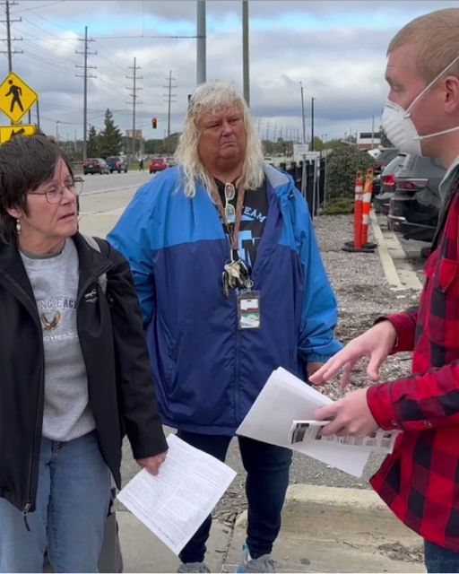 Three workers having a conversation outdoors, one holding papers