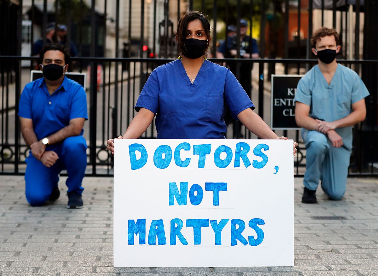 Doctors and nurses kneel in front of Downing Street in London, Thursday, May 28, 2020. (AP Photo/Frank Augstein)