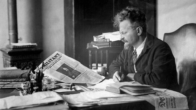Black and white historical photograph of Leon Trotsky reading The Militant newspaper at his desk