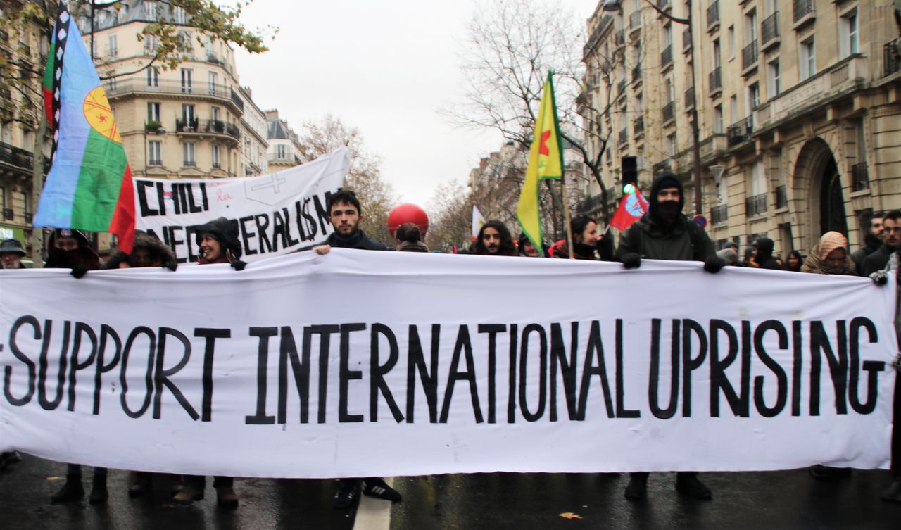 Protesters hold signs in solidarity with uprisings around the world