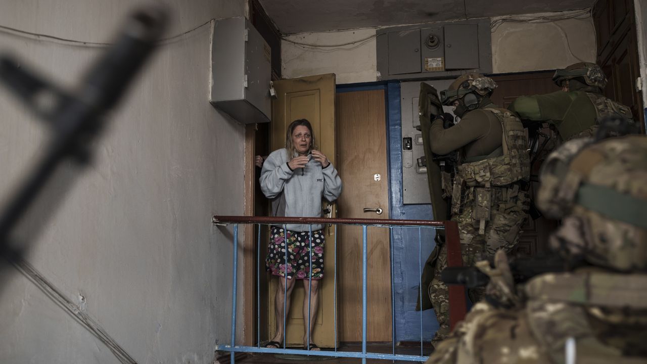 A woman looks as Security Service of Ukraine (SBU) agents enter a building during an operation to arrest suspected Russian "collaborators" in Kharkiv, Ukraine, Thursday, April 14, 2022. [AP Photo/Felipe Dana]
