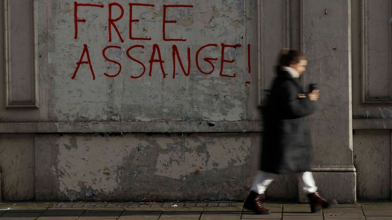 A pedestrian passes pro-Assange graffitti outside Westminster Magistrates Court in London. (AP Photo/Kirsty Wigglesworth)