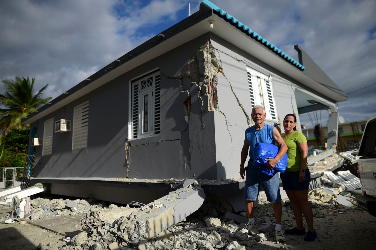 67-year-old William Mercuchi, center, and his daughter Joan pose for photos in front of their house that collapsed after the previous day's magnitude 6.4 earthquake in Yauco, Puerto Rico, Wednesday, Jan. 8, 2020. More than 250,000 Puerto Ricans remained without water on Wednesday and another half a million without power, which also affected telecommunications. (AP Photo/Carlos Giusti)