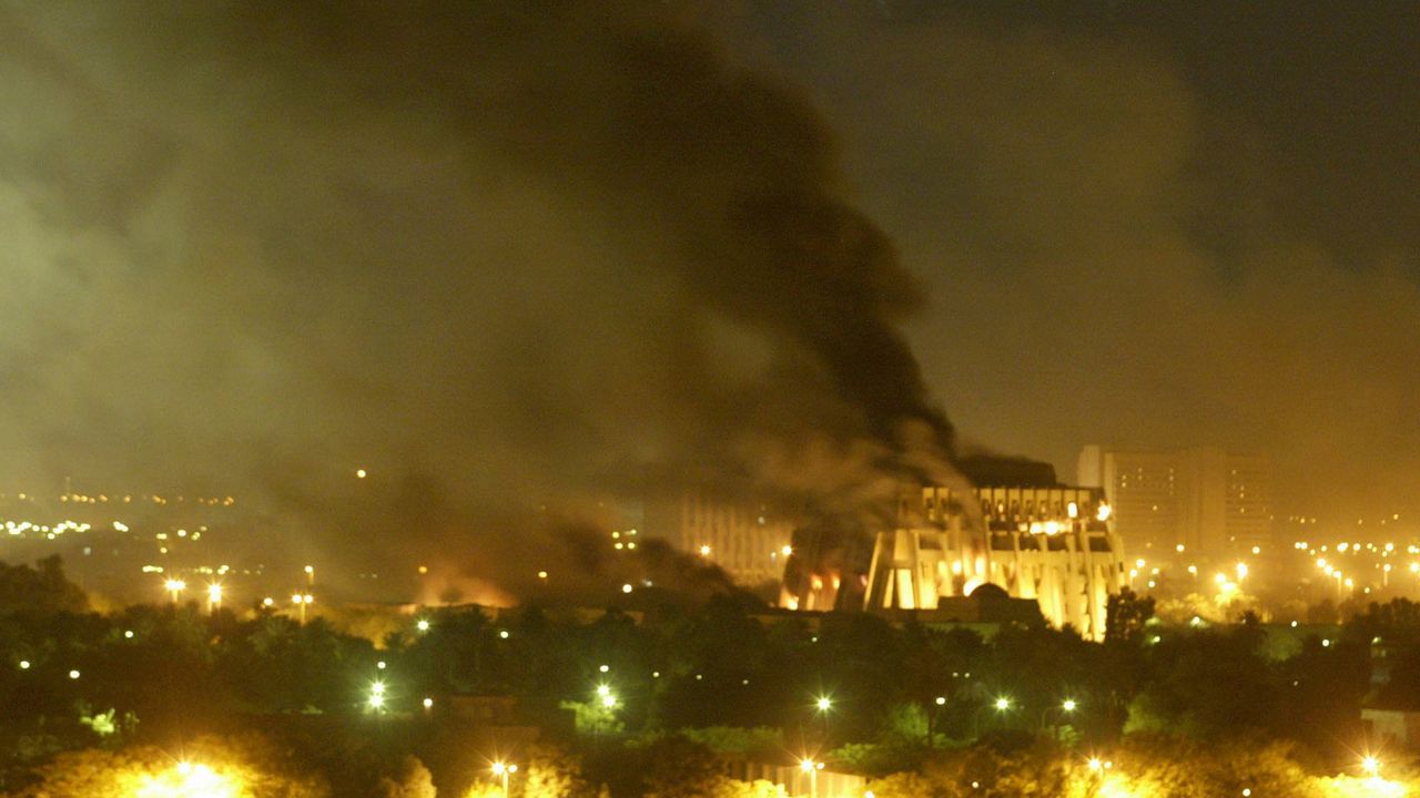 На этой фотографии из архива, сделанной 21 марта 2003 года, правительственное здание горит во время сильной бомбардировки Багдада, силами, возглавляемыми США. [AP Photo/Джером Делэй]