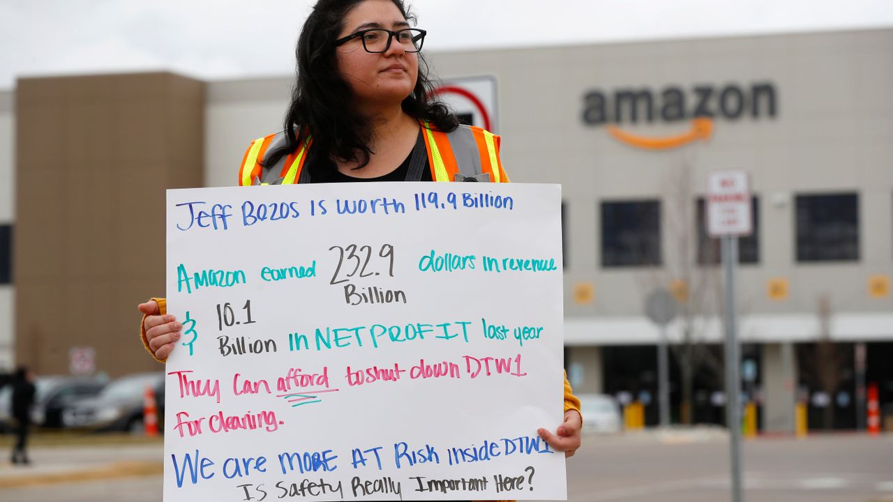 Breana Avelar, a processing assistant, holds a sign outside the Amazon DTW1 fulfillment center in Romulus, Michigan, April 1, 2020 [Credit: AP Photo/Paul Sancya]