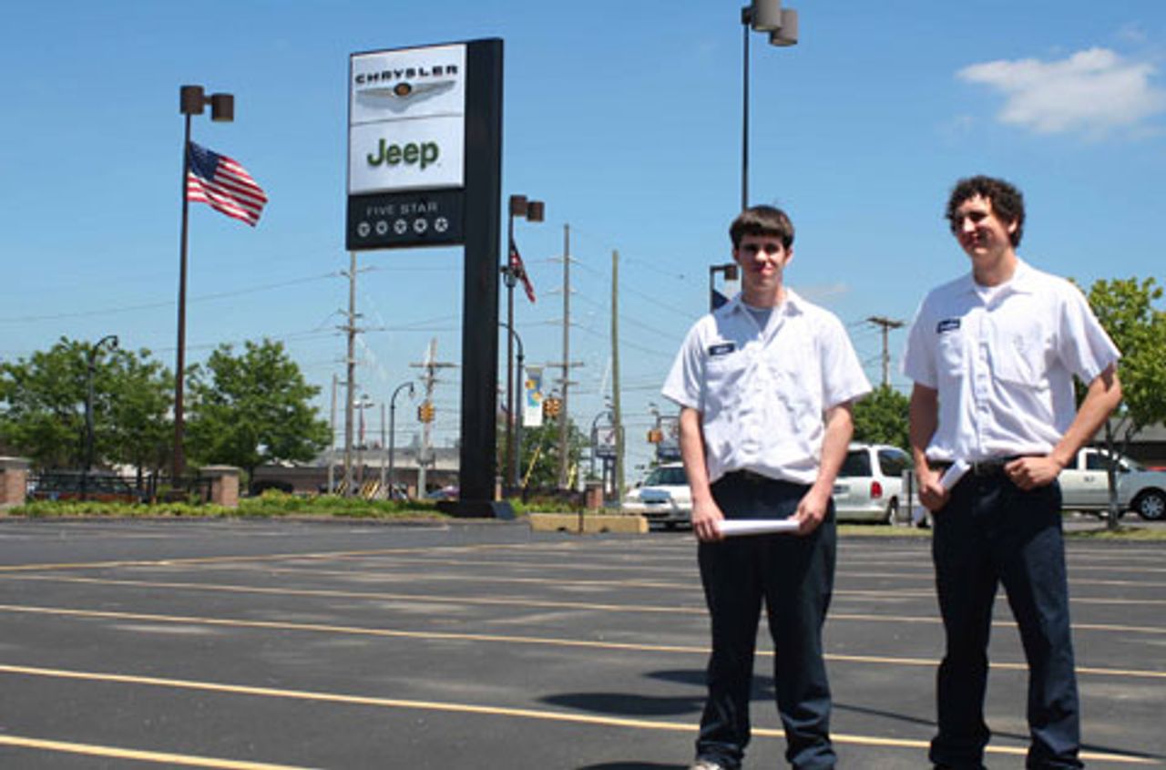 Mick and Matthew stand in the car lot that once was full of new and used vehicles